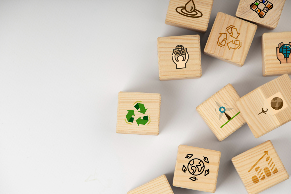 Algunos cubos de madera de color de pino ocupan la mitad derecha de la imagen. Todos ellos tienen diferentes motivos relacionados con objetivos de sostenibilidad.