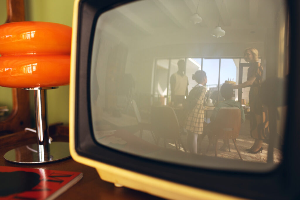 Vista d'un televisor molt antic amb el reflex d'una família a la pantalla.